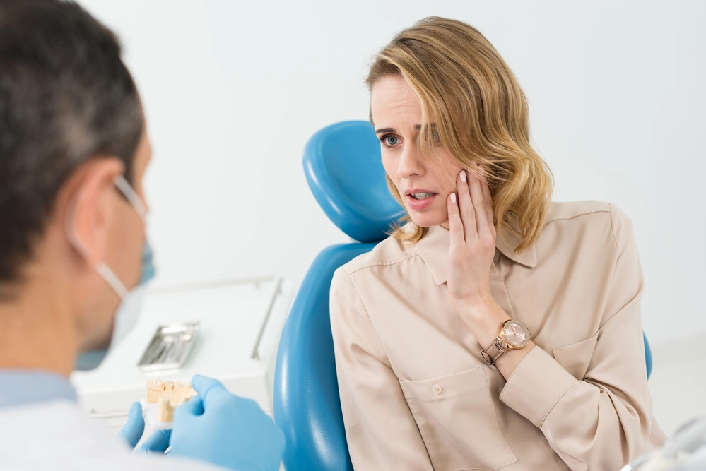 A-woman-in-a-dentist-chair-holding-her-cheek