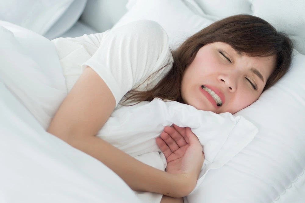 Woman-in-bed-hugging-pillow-while-grinding-her-teeth