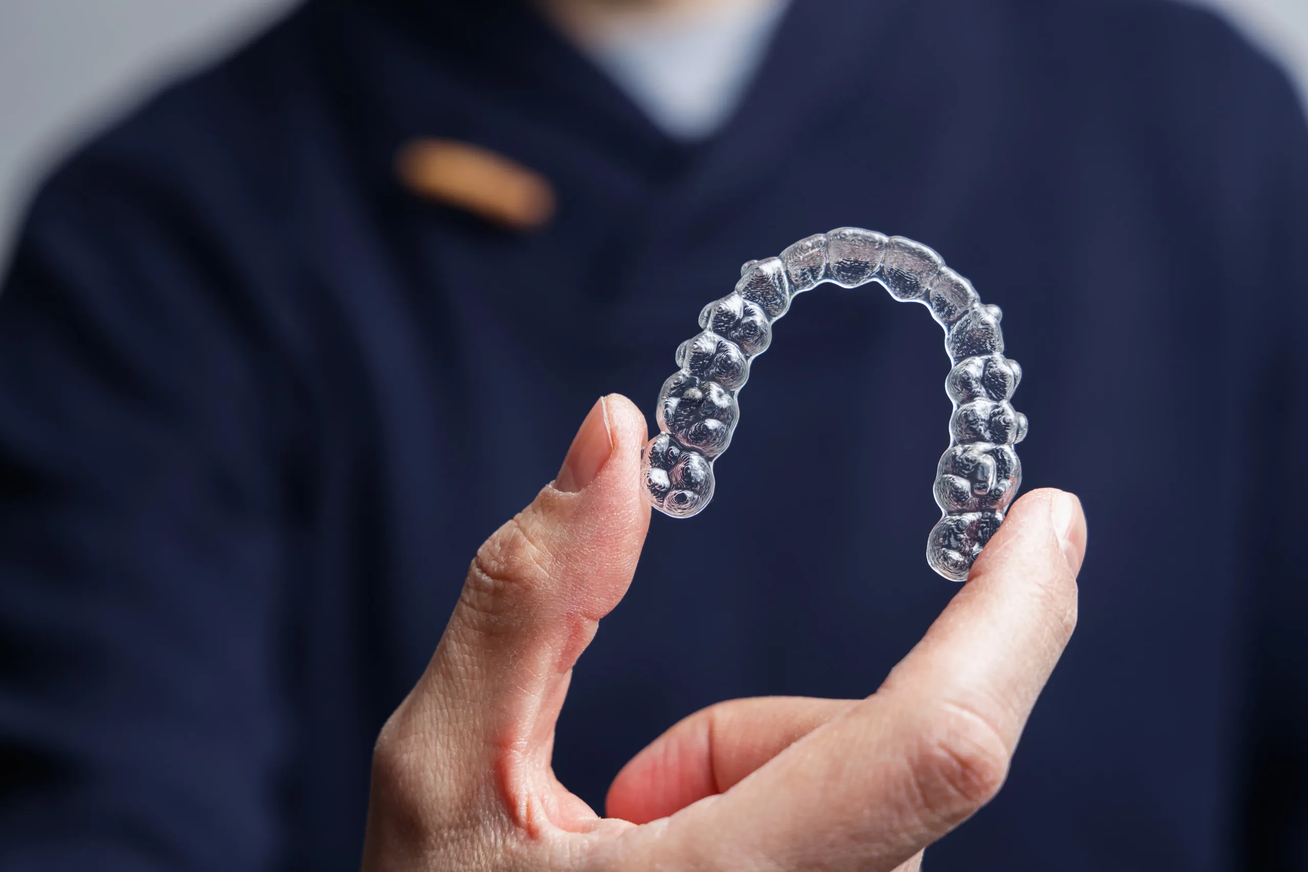 A person holding Invisalign aligners in their hands.