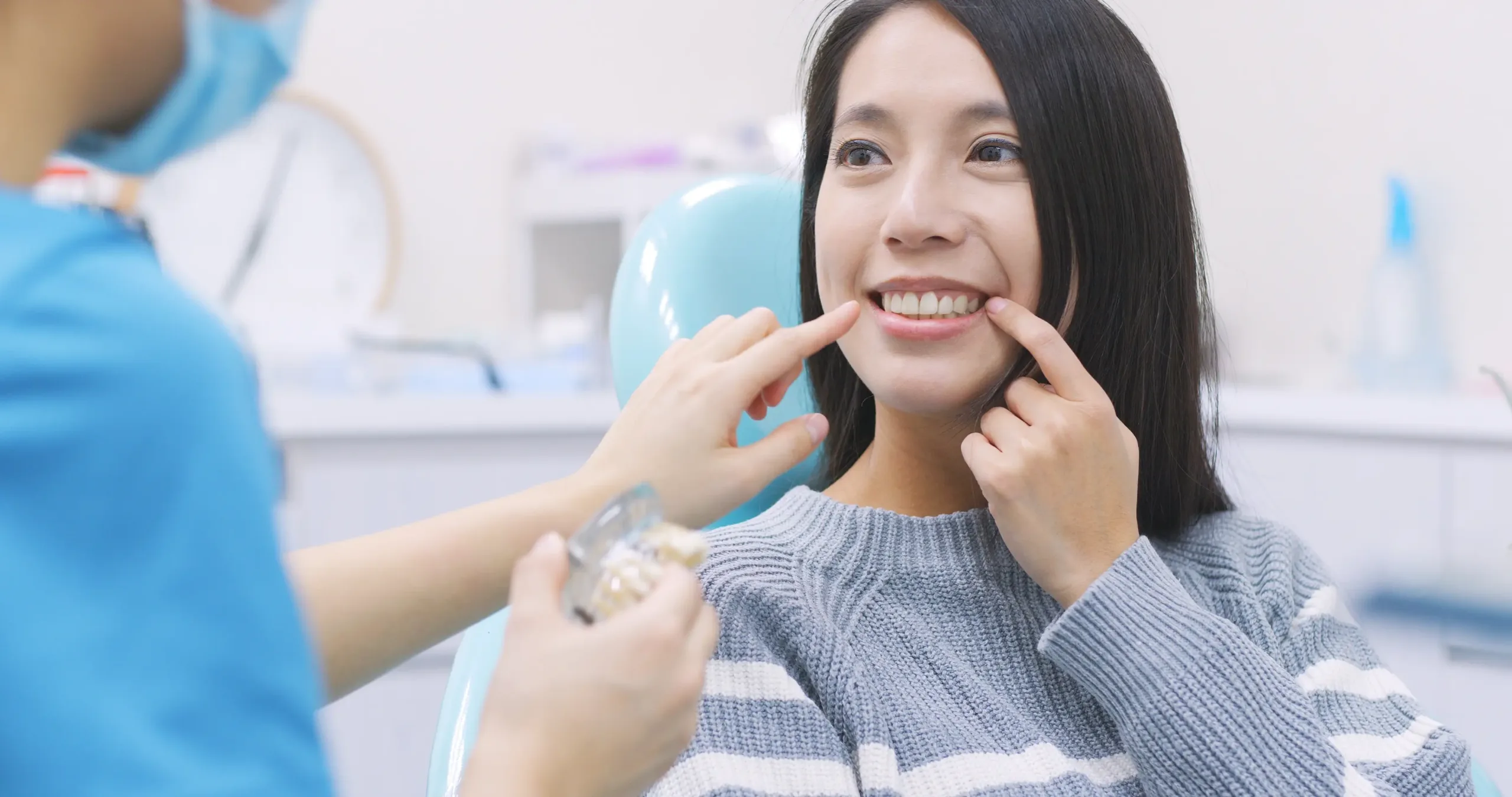 Woman in dentist chair showing her teeth to the dentist