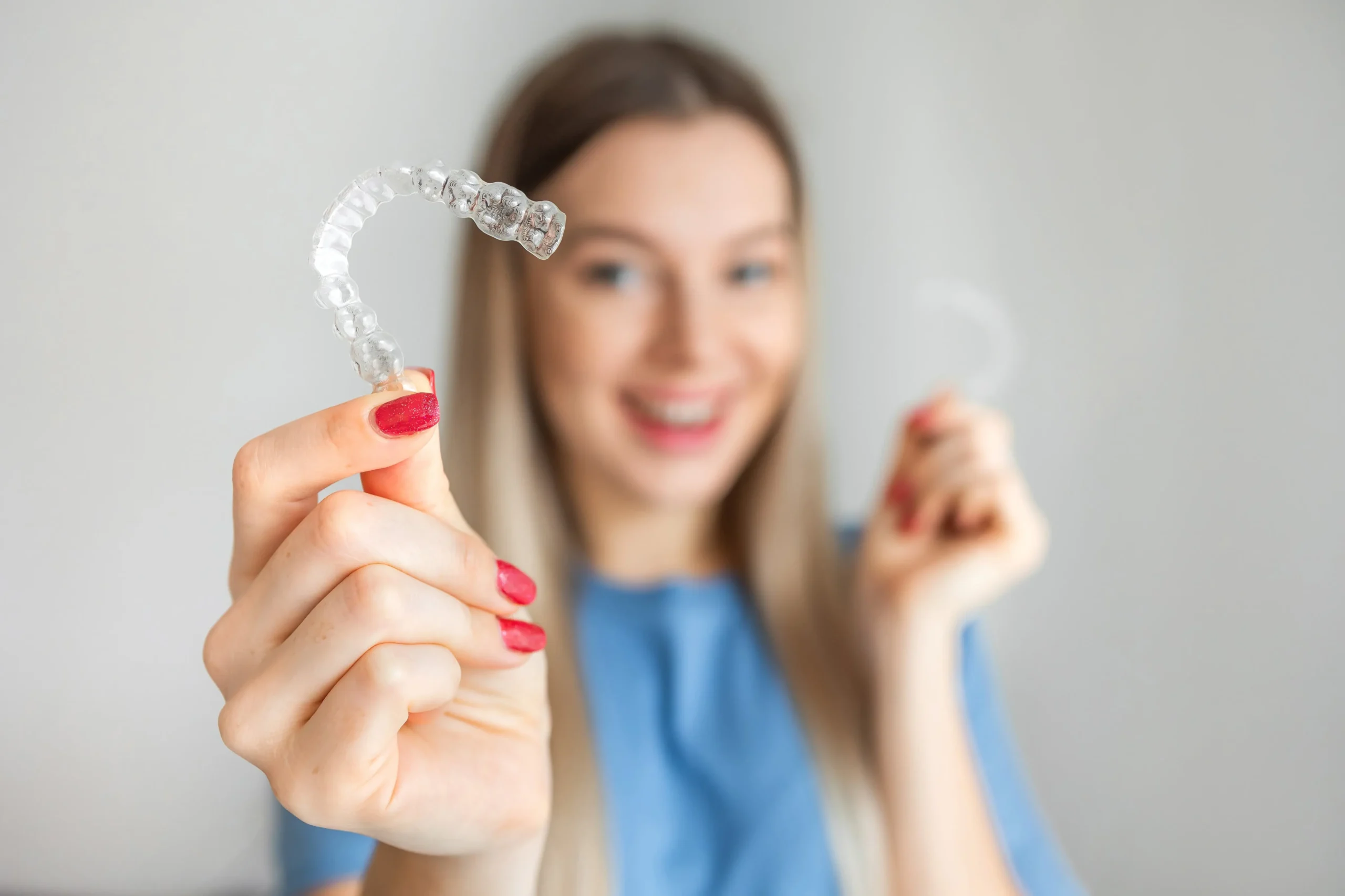 young woman smiling and showing Invisalign braces