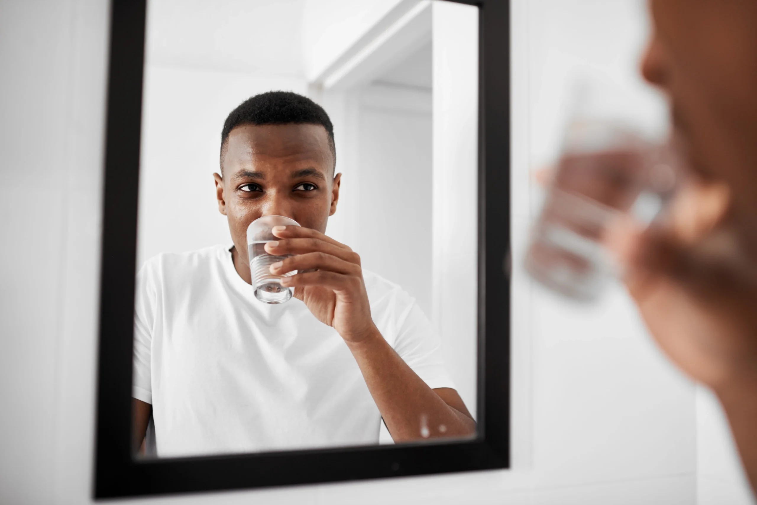 Man looking in the mirror while drinking water